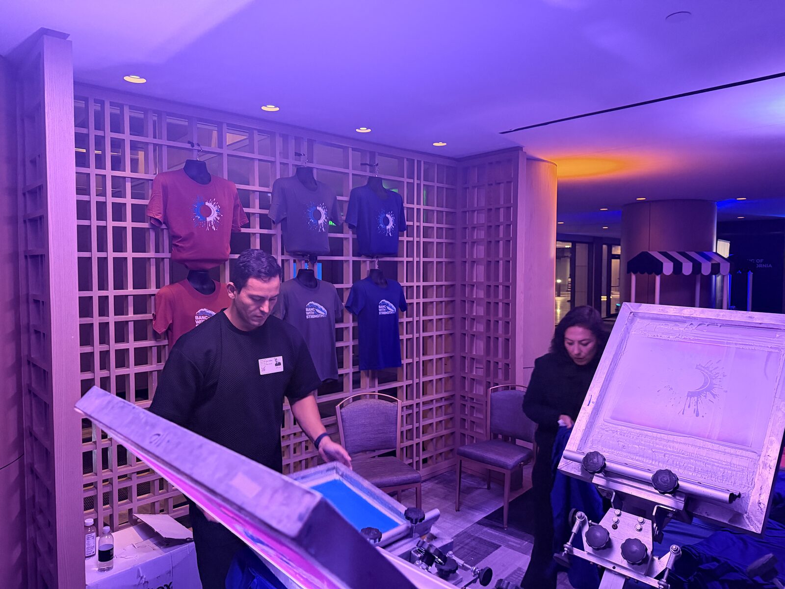 A wall of finished event shirts printed on site